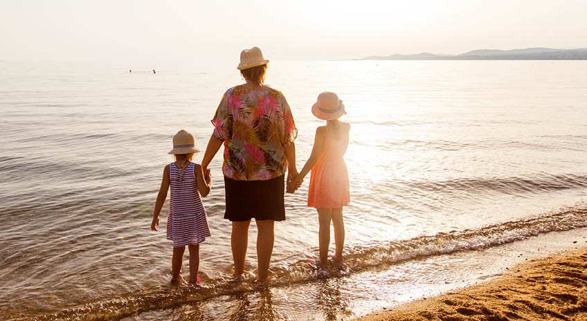 woman with two children on a beach at sunset
