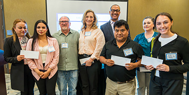 Diverse group of small business owners each holding a grant check.