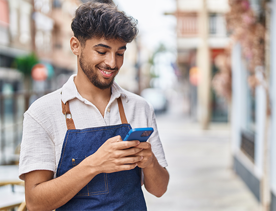 Man in apron texting on phone